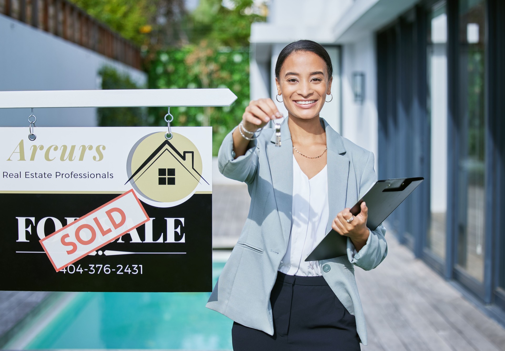 Shot of a young female real estate agent holding keys to a new house that's been sold